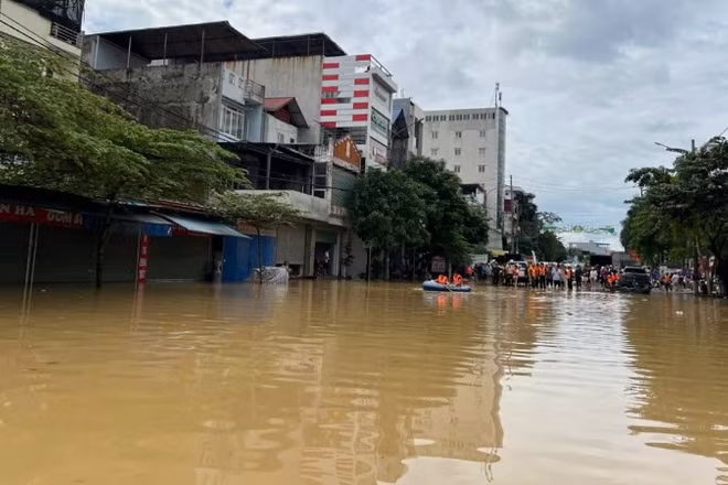 Ngập úng tại khu vực ngã tư san nền, phường Phan Đình Phùng. Phía xa là lực lượng chức năng, người dân tập trung hỗ trợ các thuyền đón người từ vùng ngập ra. (Ảnh: TUẤN SƠN).