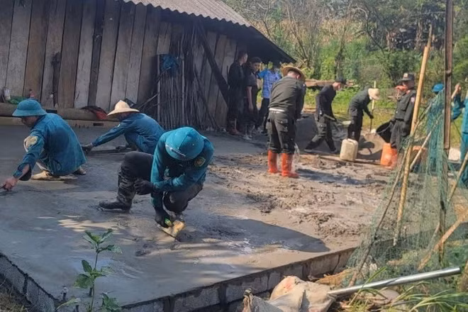 Công an và dân quân tự vệ hỗ trợ đổ bê tông nền nhà cho hộ nghèo ở xã Hiệp Lực. (Ảnh: THÀNH TÂM)
