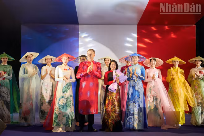Đại sứ Pháp Olivier Brochet (áo dài đỏ) chúc mừng nhà thiết kế Hàn Phượng (cầm hoa) sau màn trình diễn áo dài.