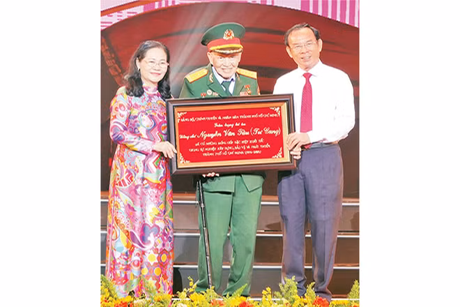 Đồng chí Nguyễn Văn Nên, Ủy viên Bộ Chính trị; Bí thư Thành ủy Thành phố Hồ Chí Minh trao bảng tôn vinh Đại tá, Anh hùng Lực lượng Vũ trang nhân dân Nguyễn Văn Tàu (Tư Cang).