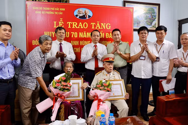 Đồng chí Nguyễn Quốc Chung, Phó Bí thư Thường trực Tỉnh ủy (thứ tư hàng sau từ trái qua) trao Huy hiệu 70 năm tuổi Đảng tặng vợ chồng Anh hùng lực lượng vũ trang nhân dân Tạ Lưu.
