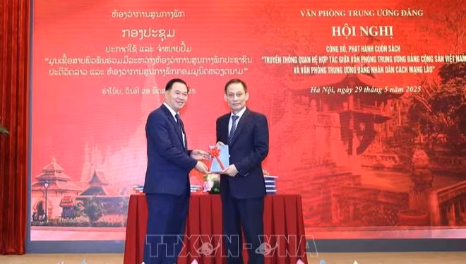 Đồng chí Lê Hoài Trung, Bí thư Trung ương Đảng, Chánh Văn phòng Trung ương Đảng tặng sách cho đồng chí đồng chí Thongsalith Mangnomek, Bí thư Trung ương Đảng, Chánh Văn phòng Trung ương Đảng Nhân dân Cách mạng Lào. (Ảnh: TTXVN) 