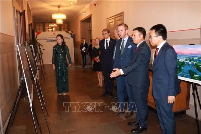 Đại sứ Trần Văn Tuấn giới thiệu triển lãm ảnh Việt Nam với ông Andreas Carlson, Bộ trưởng phụ trách Cơ sở Hạ tầng và Nhà ở Thụy Điển. 