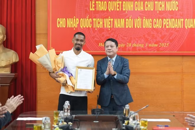 Đại diện Sở Tư pháp thành phố Hà Nội trao quyết định nhập quốc tịch Việt Nam cho cầu thủ Cao Pendant Quang Vinh. (Ảnh: PHAN THẠCH).
