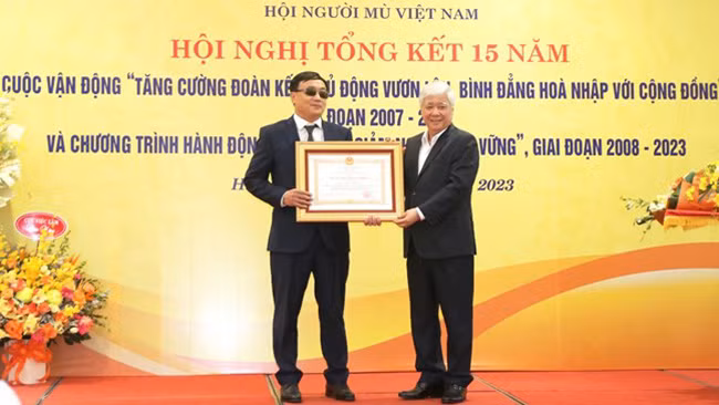 Đồng chí Đỗ Văn Chiến trao Huân chương Lao động hạng Ba tặng ông Phạm Xuân Trường, Ủy viên Ban Thường vụ Hội Người mù Việt Nam, với những đóng góp vì người mù. (Ảnh: mattran.org.vn)