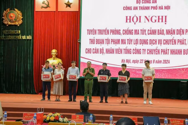 Phó Giám đốc Công an thành phố Hà Nội Nguyễn Thanh Tùng trao ấn phẩm tuyên truyền phòng chống ma túy cho đại diện các công ty chuyển phát nhanh bưu điện EMS.
