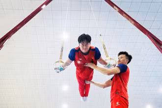 Huấn luyện viên Trương Minh Sang hỗ trợ vận động viên trong bài tập vòng treo.