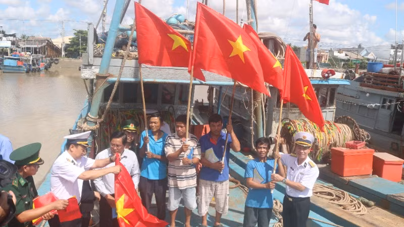 Ngư dân xã Đại An, tỉnh Vĩnh Long được cán bộ, chiến sĩ Hải quân Vùng 2 trao tặng cờ Tổ quốc.