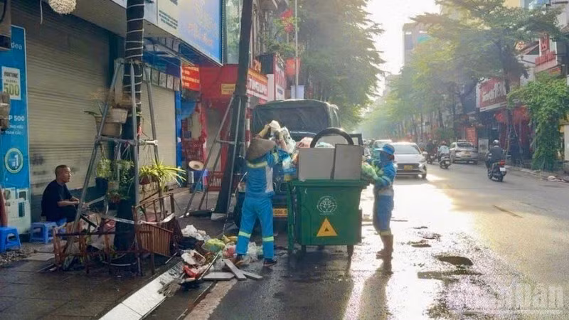 Công nhân môi trường dọn dẹp, thu gom rác sau mưa bão trên phố Khâm Thiên (Hà Nội). 