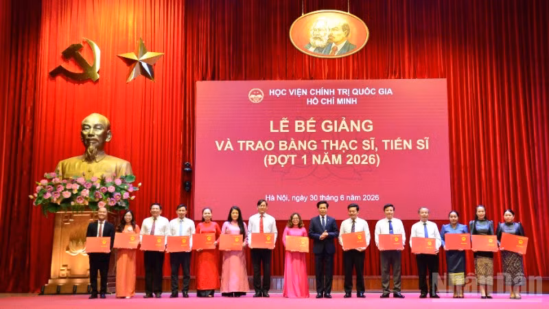 Đồng chí Hoàng Phúc Lâm, Phó Bí thư Đảng ủy, Phó Giám đốc Học viện Chính trị quốc gia Hồ Chí Minh trao bằng tiến sĩ cho các học viên. (Ảnh: PHẠM CƯỜNG)