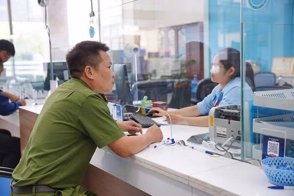 Thiếu tá Lò Văn Dũng làm thủ tục xác minh, chuyển hoàn số tiền cho người đã chuyển nhầm. Ảnh: ANH TUẤN