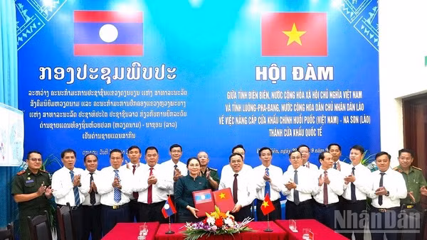 Hai đồng chí Trưởng đoàn trao biên bản hội đàm ký kết về việc thống nhất báo cáo cấp có thẩm quyền nâng cấp cặp cửa khẩu chính Huổi Puốc (Việt Nam)-Na Son (Lào) thành cửa khẩu quốc tế. (Ảnh: LÊ LAN)