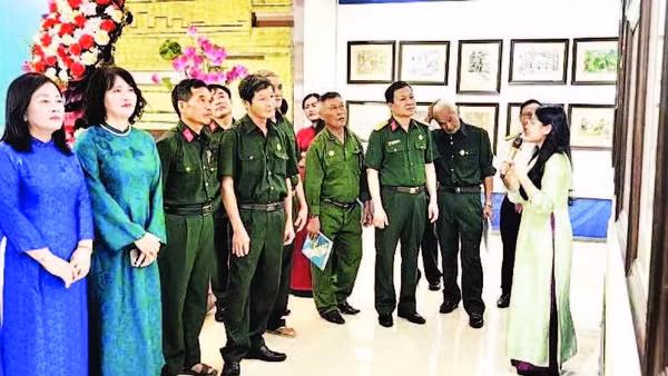 Các đại biểu và cựu chiến binh xem triển lãm tranh ký họa (Ảnh HƯƠNG GIANG)