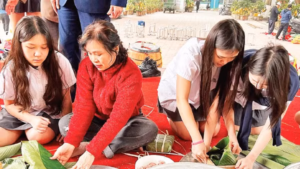 Các em học sinh trải nghiệm gói bánh chưng cùng hội viên Câu lạc bộ Liên thế hệ tự giúp nhau phường Khương Đình (thành phố Hà Nội).