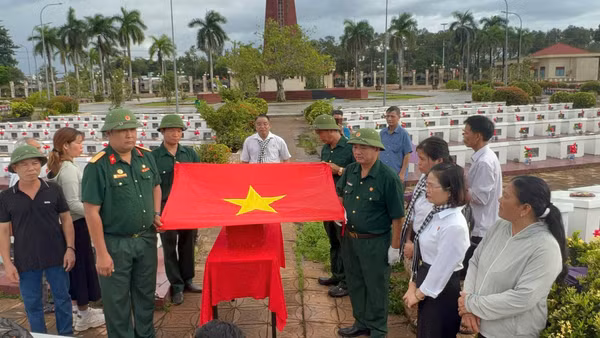 Nghi thức phủ Quốc kỳ, trước khi đưa liệt sĩ Lê Duy Nhẫn về quê hương. (Ảnh: THÀNH TRUNG)
