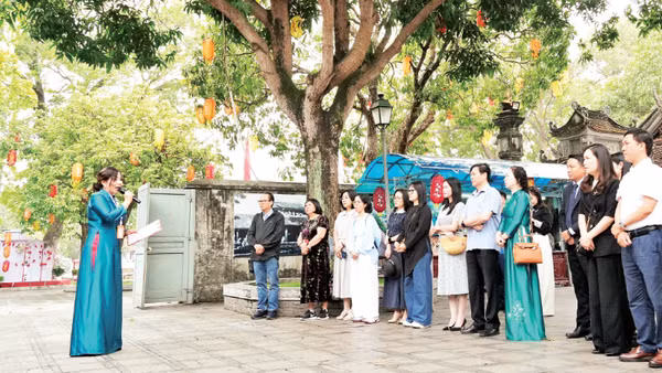 Du khách nghe hướng dẫn viên giới thiệu về Đền Đô (tỉnh Bắc Ninh). (Ảnh: ĐỒNG THÚY)