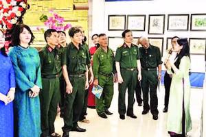 Các đại biểu và cựu chiến binh xem triển lãm tranh ký họa (Ảnh HƯƠNG GIANG)