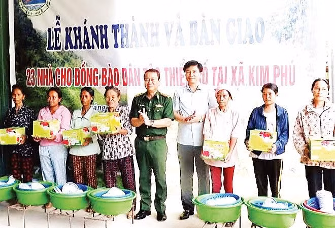 Các đại biểu tặng quà cho các gia đình người dân tộc được nhận nhà mới trong dịp này.