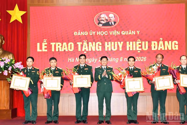 Thiếu tướng, Phó Giáo sư, Tiến sĩ Nguyễn Văn Nam, Ủy viên Ban thường vụ Đảng ủy, Phó Chính ủy Học viện Quân y trao Huy hiệu 35 năm tuổi Đảng và tặng hoa chúc mừng 6 đồng chí thuộc Đảng bộ Học viện Quân y. (Ảnh: TUẤN DŨNG)