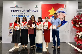 Nhà thơ, nhà báo Huỳnh Mai Liên (mặc áo dài trắng) trong buổi ra mắt tập thơ "Bốn mùa cờ bay". 