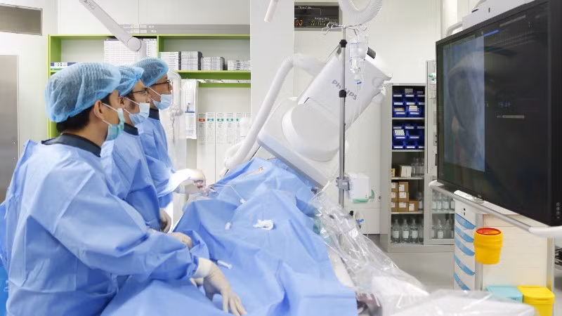 Ê kíp thực hiện kỹ thuật nút động mạch phế quản dưới hướng dẫn của hệ thống chụp mạch số hóa xóa nền.