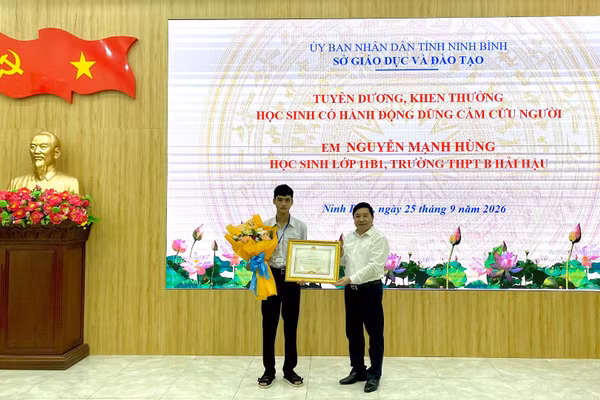 Đồng chí Nguyễn Tiến Dũng, Giám đốc Sở Giáo dục và Đào tạo tỉnh Ninh Bình trao Bằng khen của Chủ tịch Ủy ban nhân dân tỉnh và tặng hoa cho em Nguyễn Mạnh Hùng. (Ảnh: YẾN TRINH)