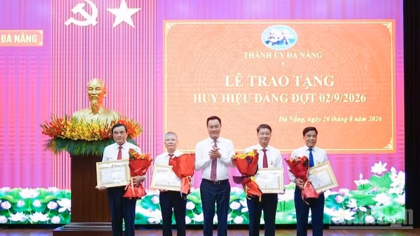 Bí thư Thành ủy Đà Nẵng Lê Ngọc Quang trao Huy hiệu Đảng và tặng hoa chúc mừng các đảng viên. (Ảnh: ANH ĐÀO)