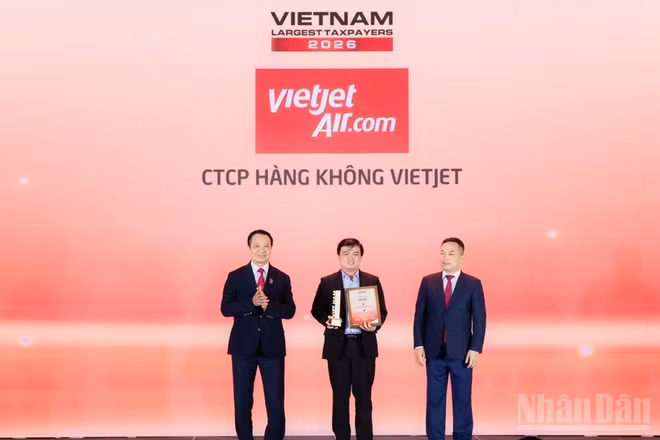 Ông Thái Trọng Cang, Kế toán trưởng Vietjet (đứng giữa) nhận bằng khen và cúp vinh danh doanh nghiệp dẫn đầu nhóm doanh nghiệp hàng không, logistics tư nhân nộp ngân sách lớn nhất Việt Nam năm 2025. (Ảnh: BẢO VY)