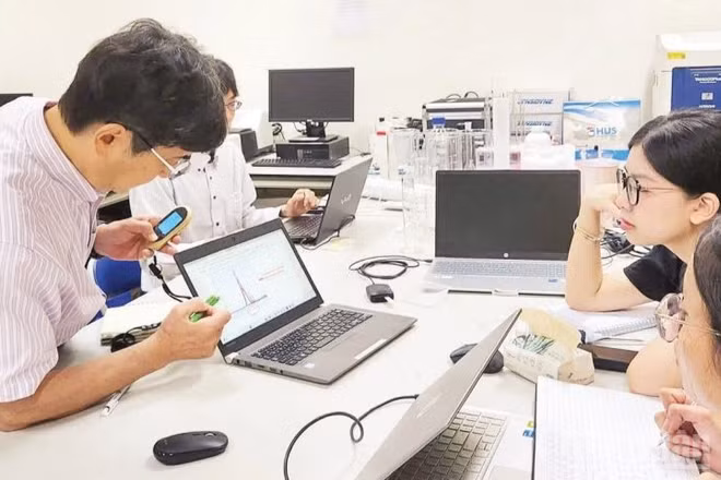 Chuyên gia Nhật Bản và các cán bộ nghiên cứu Việt Nam thảo luận tại Phòng thí nghiệm trọng điểm vật liệu tiên tiến ứng dụng trong phát triển xanh, Đại học Quốc gia Hà Nội. (Ảnh HÀ LINH)